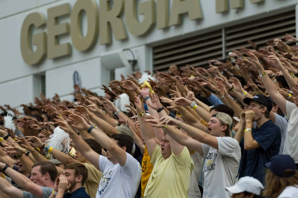 Fans at a sporting event, cheering with raised hands.